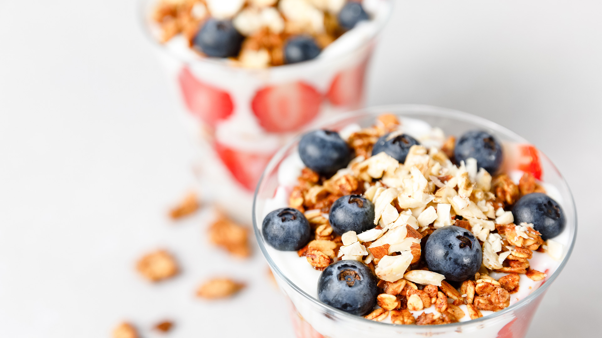 two glasses of yogurt with blueberries and granola