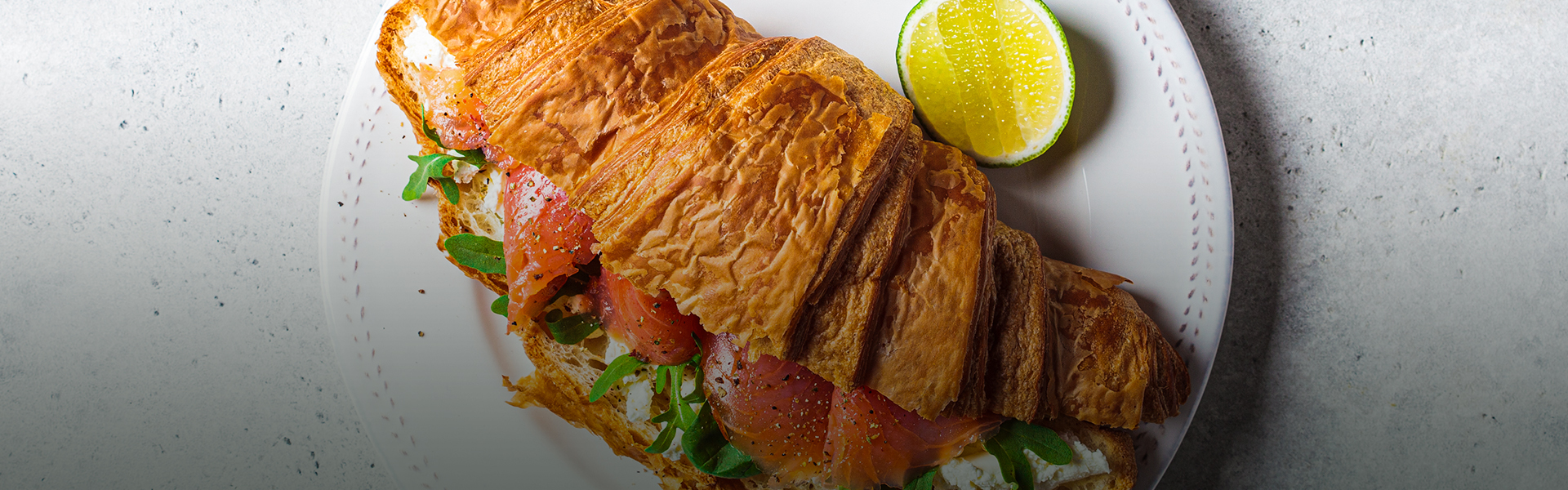 a croissant with fish and vegetables on it