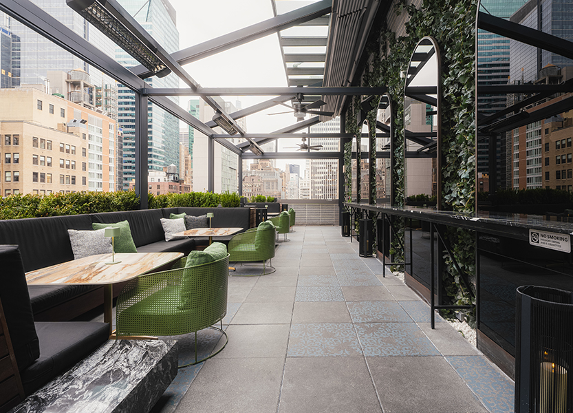 a patio with a large covered patio with green chairs and tables