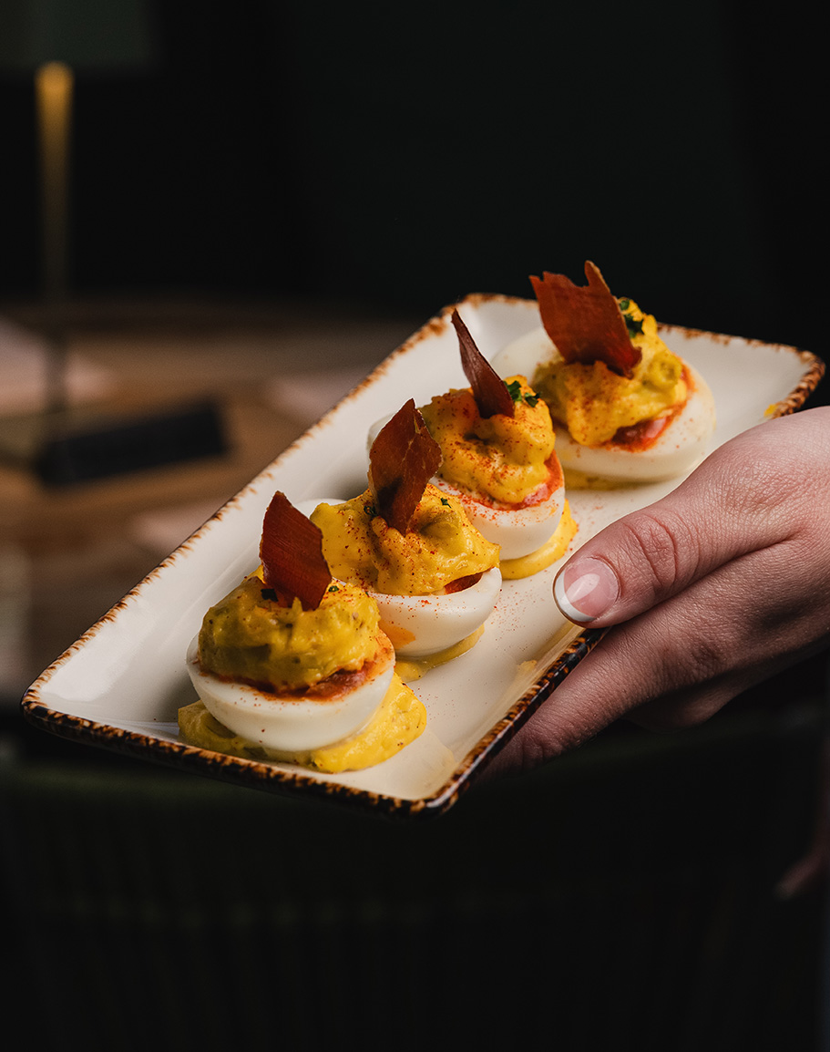 a hand holding a plate of deviled eggs