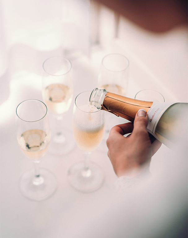 a person pouring champagne into glasses previus