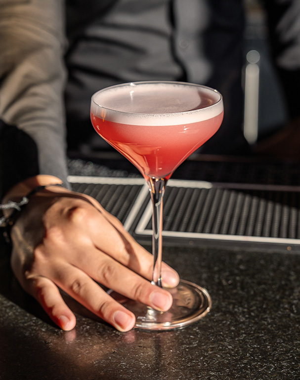 a hand holding a glass of pink liquid