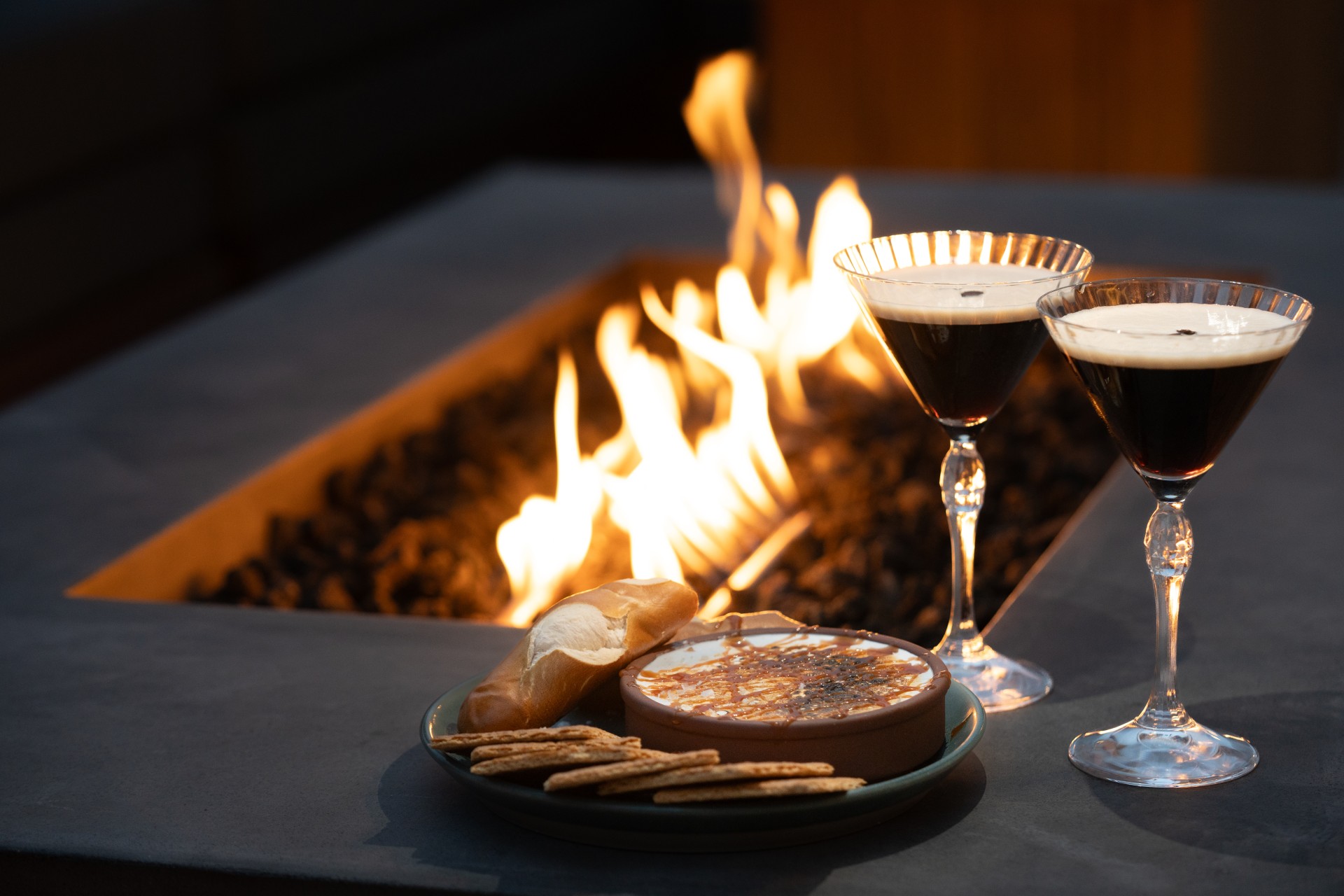 a plate of food and a drink next to a fire