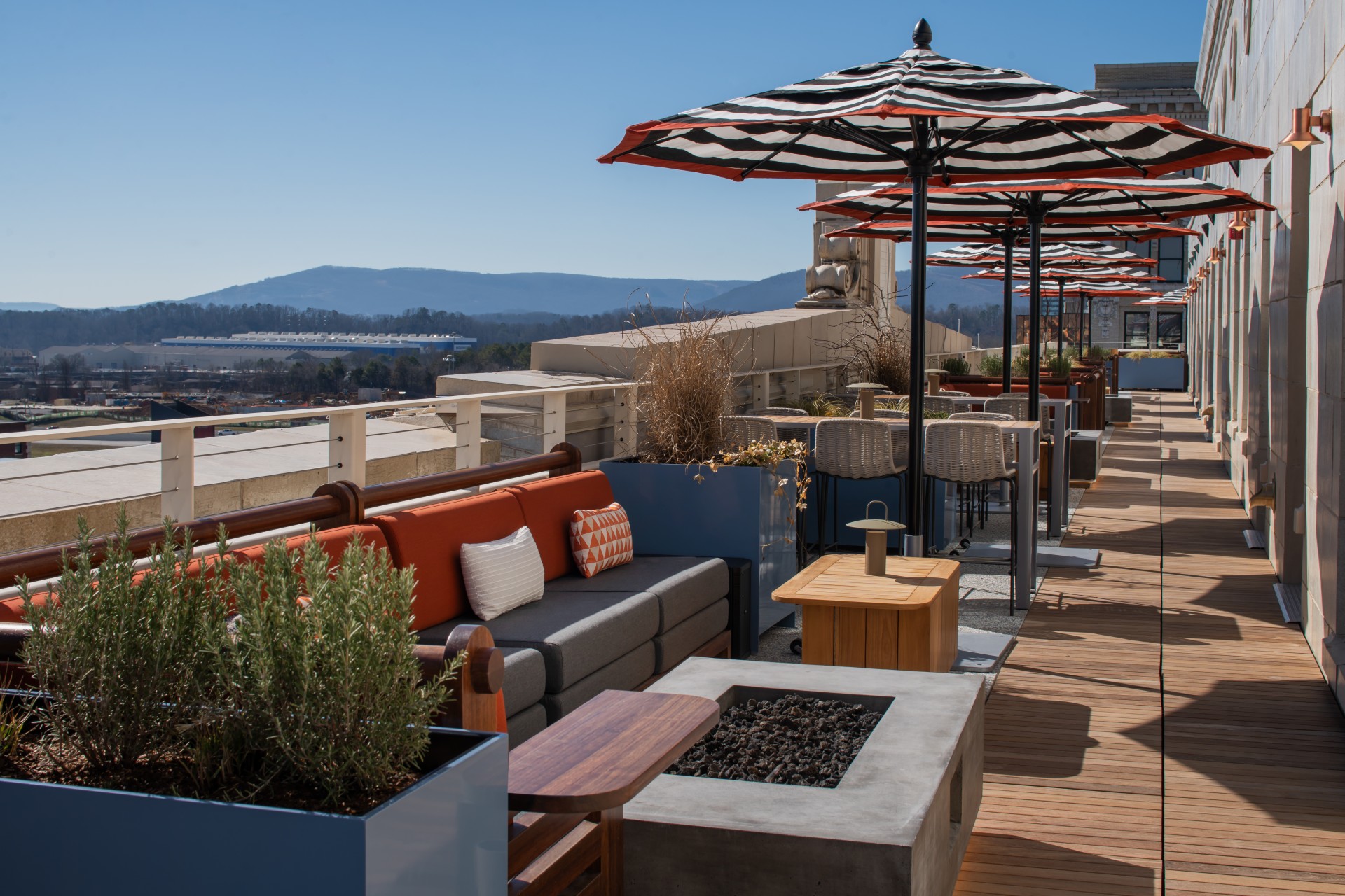 a patio with umbrellas and couches on a rooftop