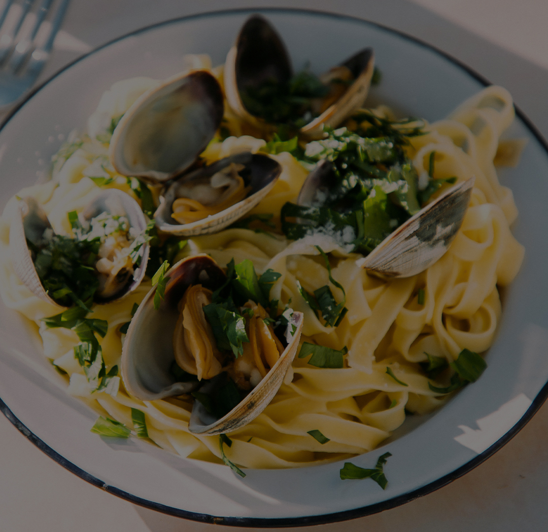 a plate of pasta with clams and parsley