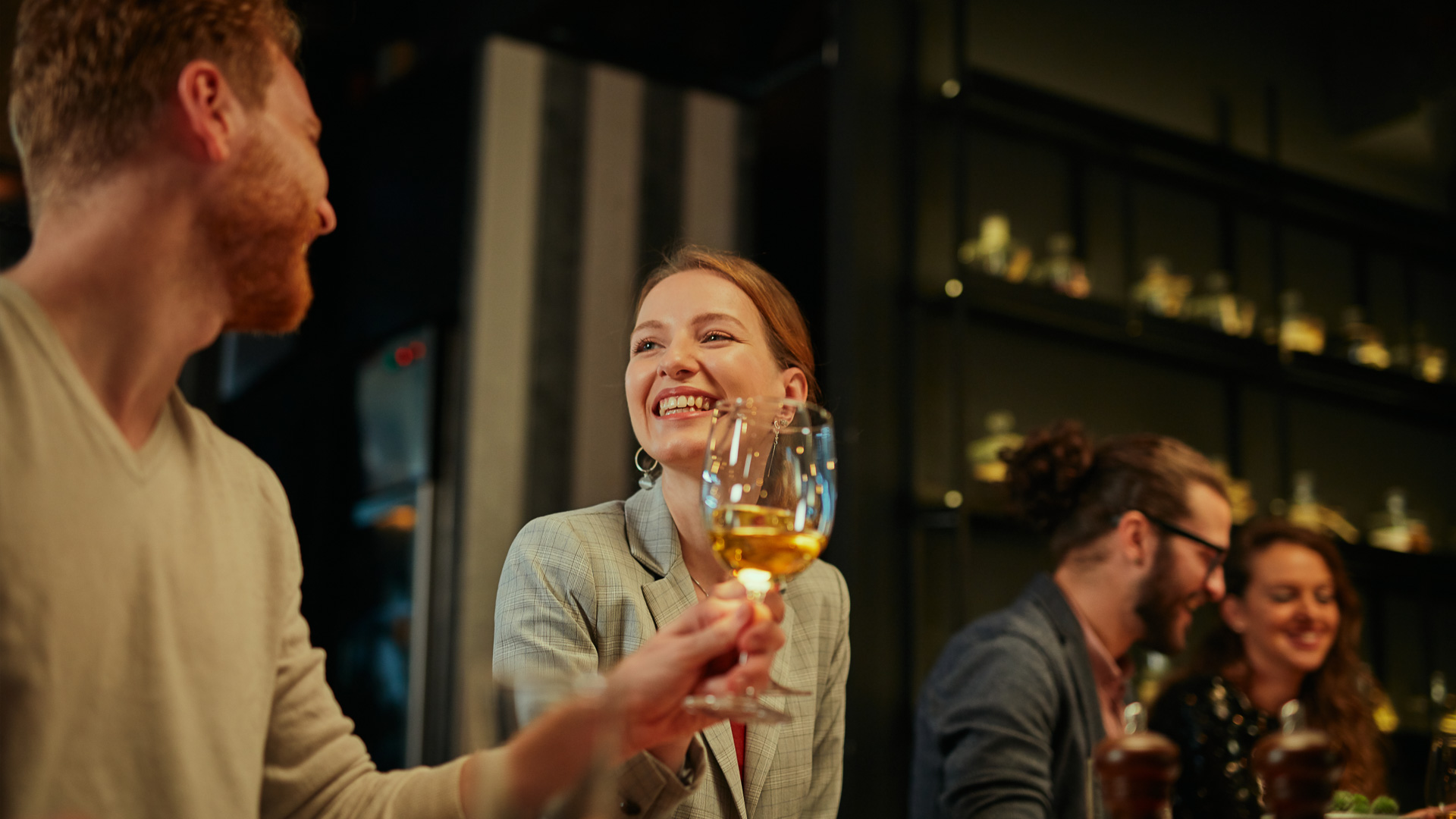 a woman smiling at a man holding a wine glass