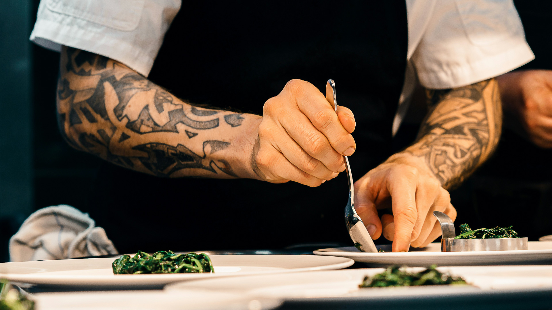 a person with tattoos on their arm and a spoon