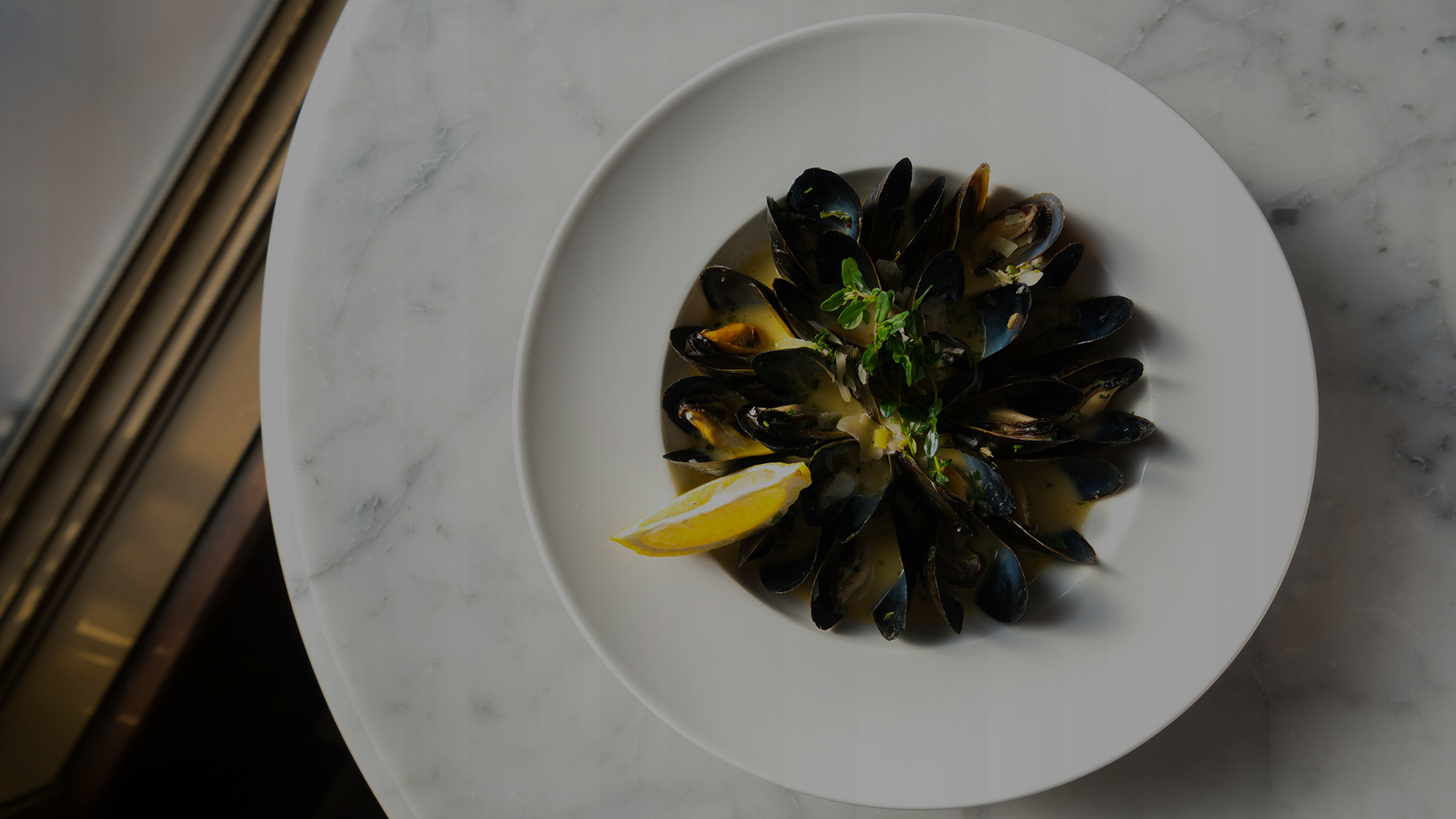 a plate of mussels with a lemon wedge