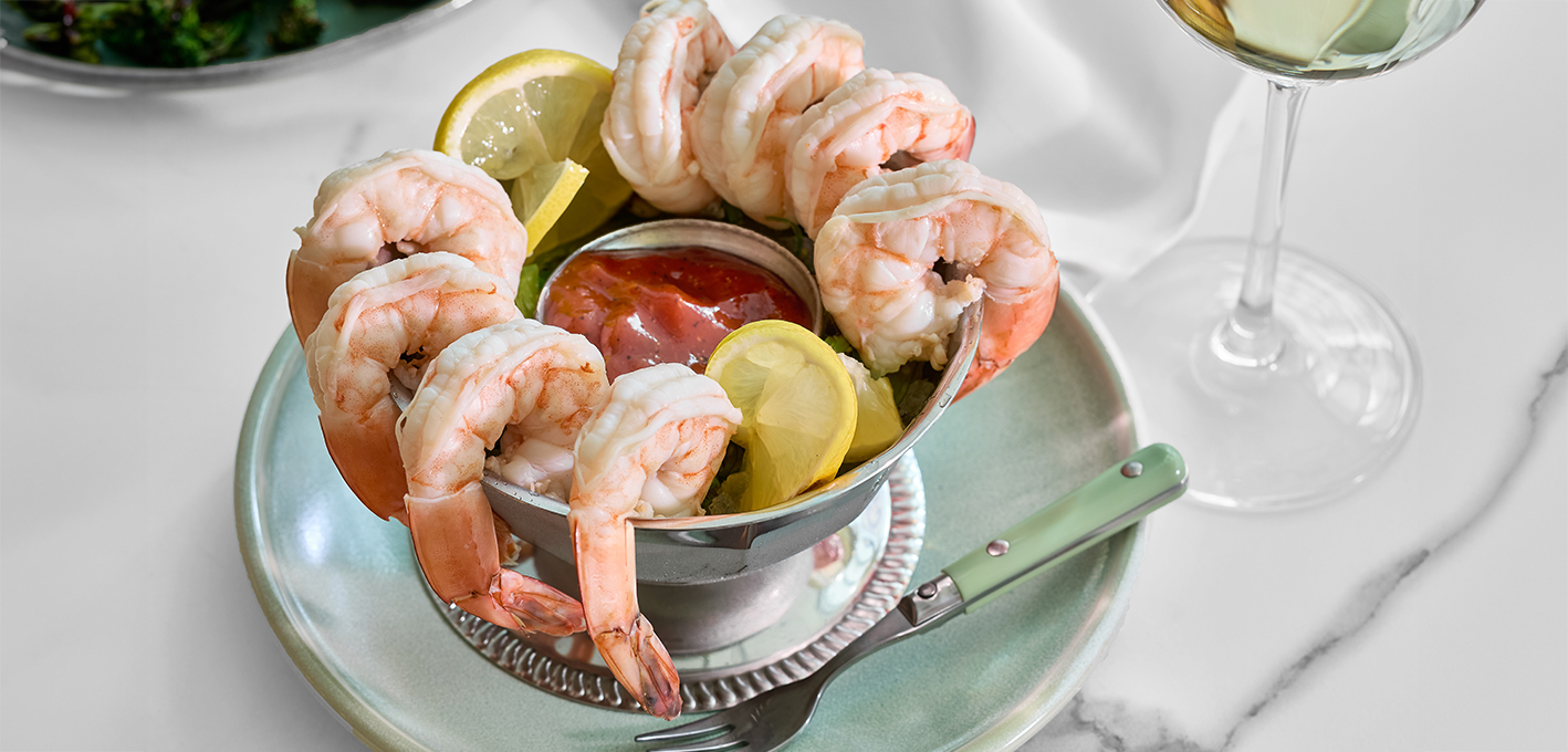 a bowl of shrimp with sauce and lemon slices