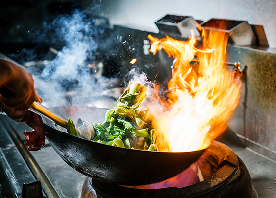 a wok with food on fire