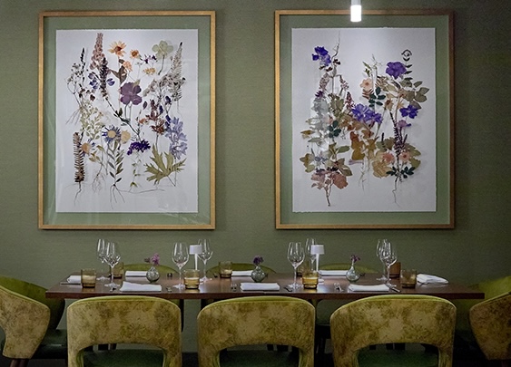 a table with chairs and framed pictures of flowers on it