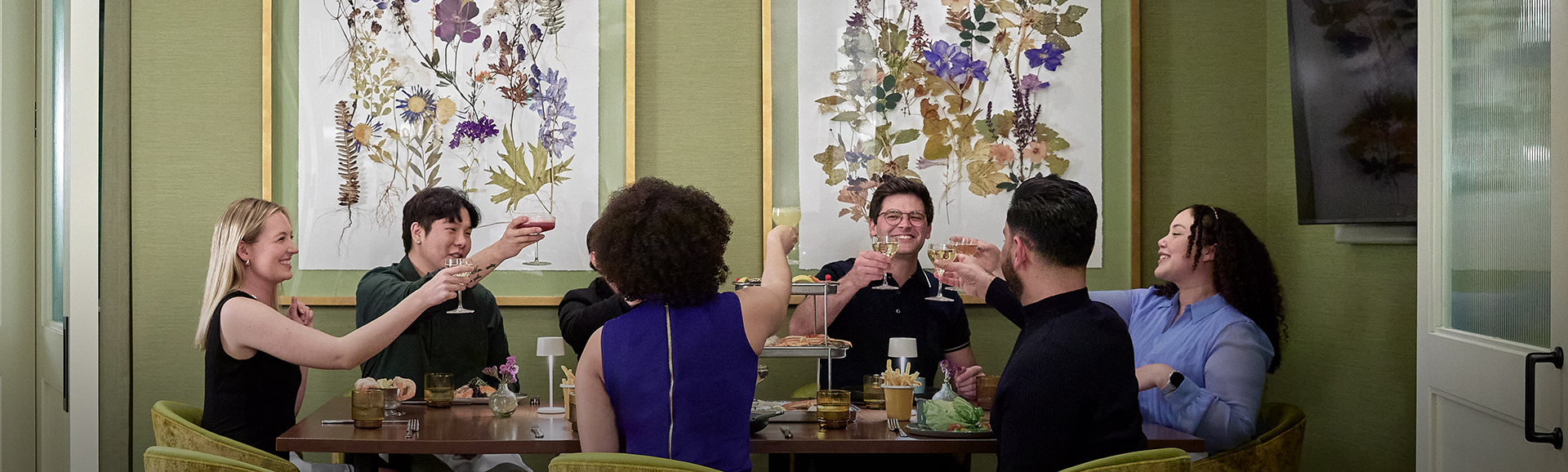 a group of people sitting at a table with food and drinks
