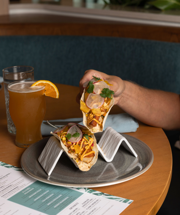 a person holding tacos on a plate