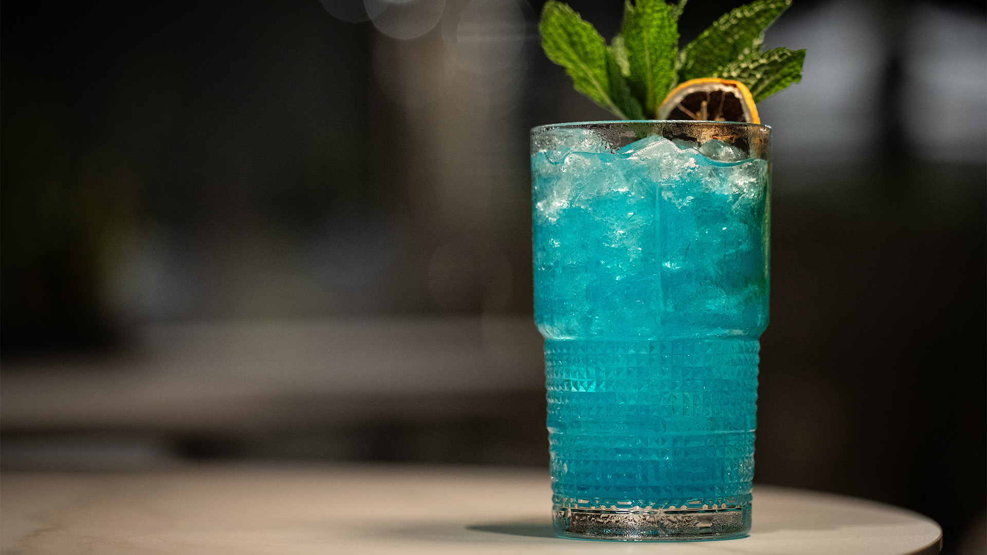 a blue drink with ice and a slice of lemon