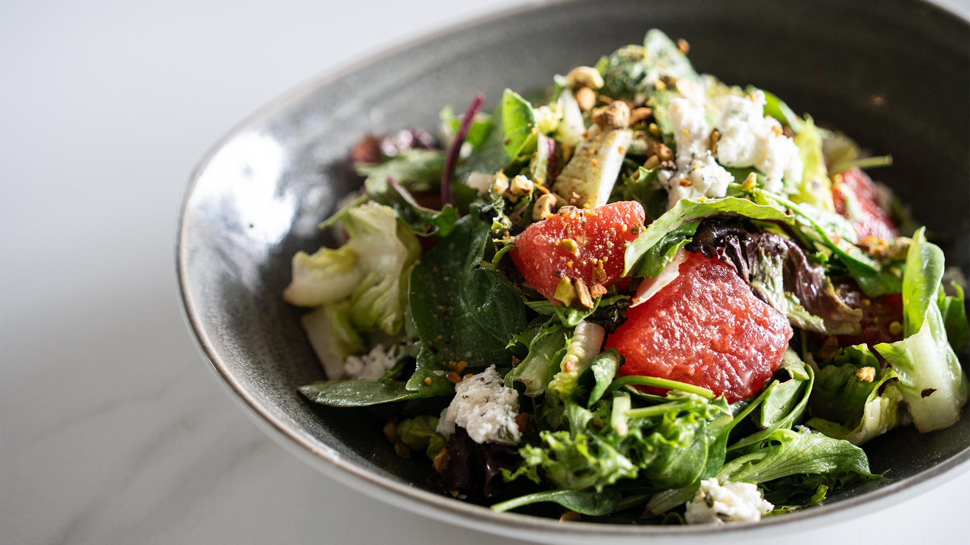 a bowl of salad with fruit and nuts