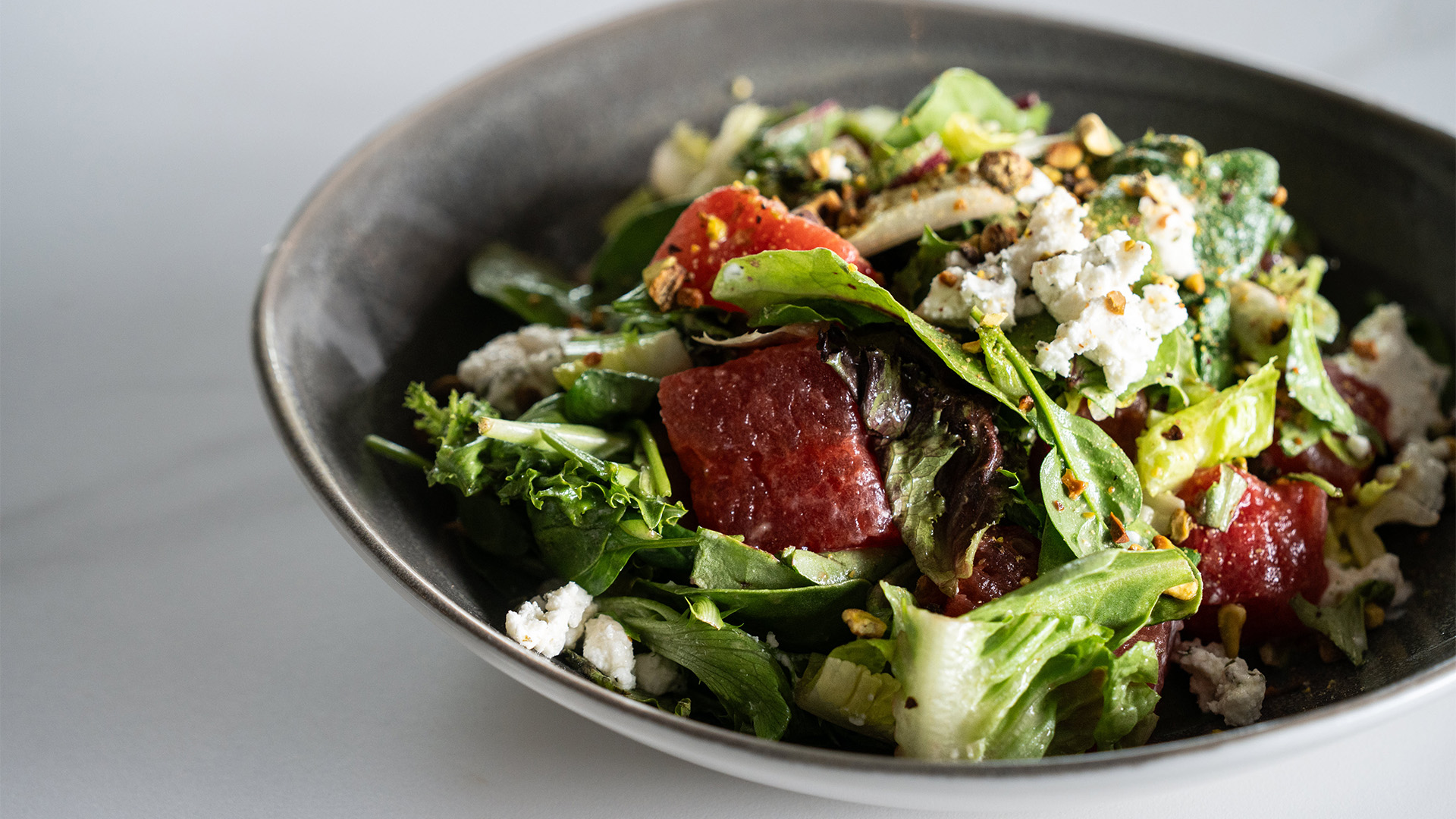 a bowl of salad with fruit and cheese