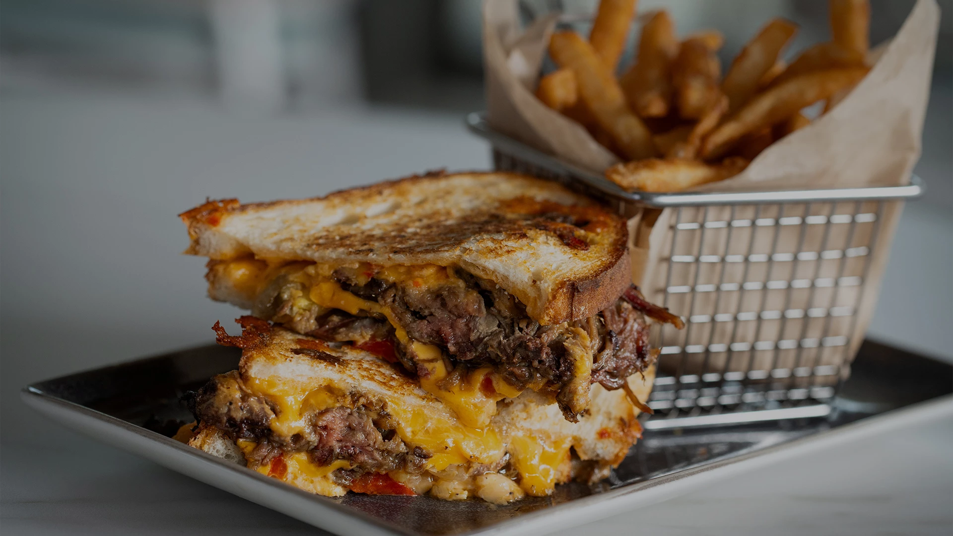 a sandwich with cheese and meat on a plate next to fries