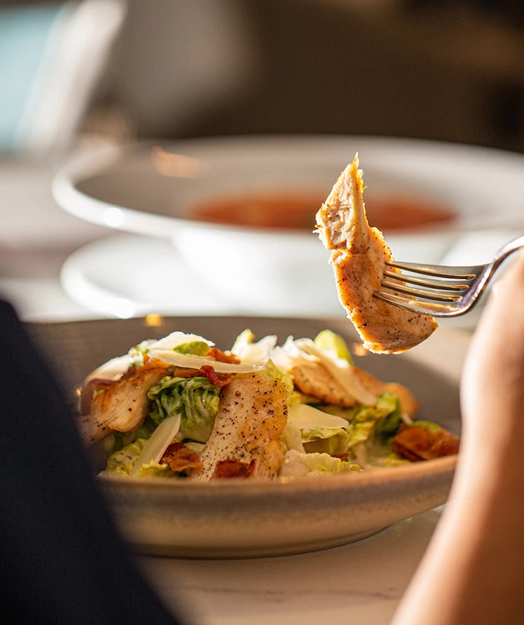 a person holding a fork over a salad