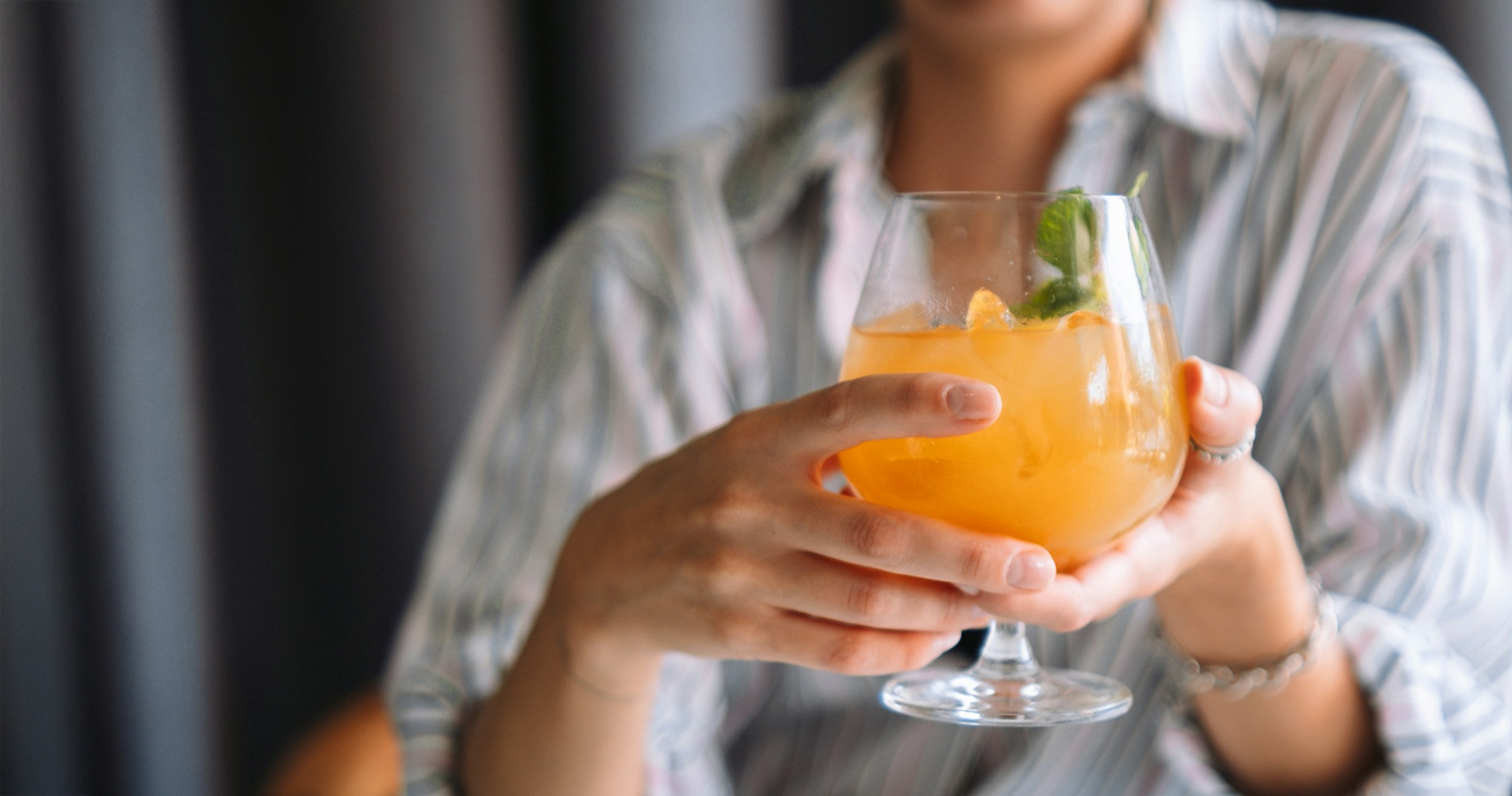 a person holding a glass of orange liquid