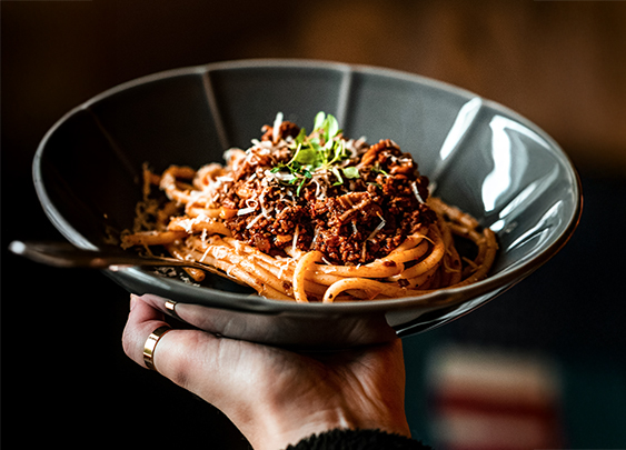 a person holding a bowl of pasta