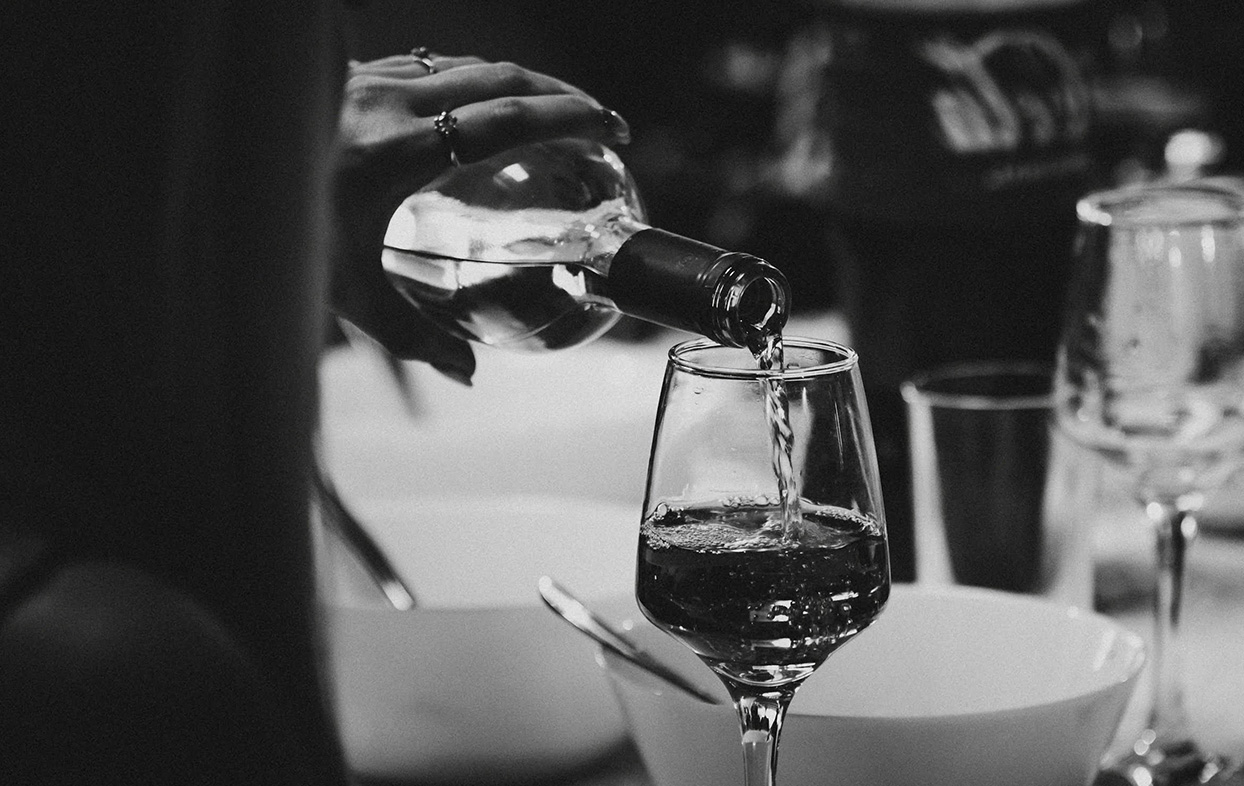 a person pouring wine into a glass