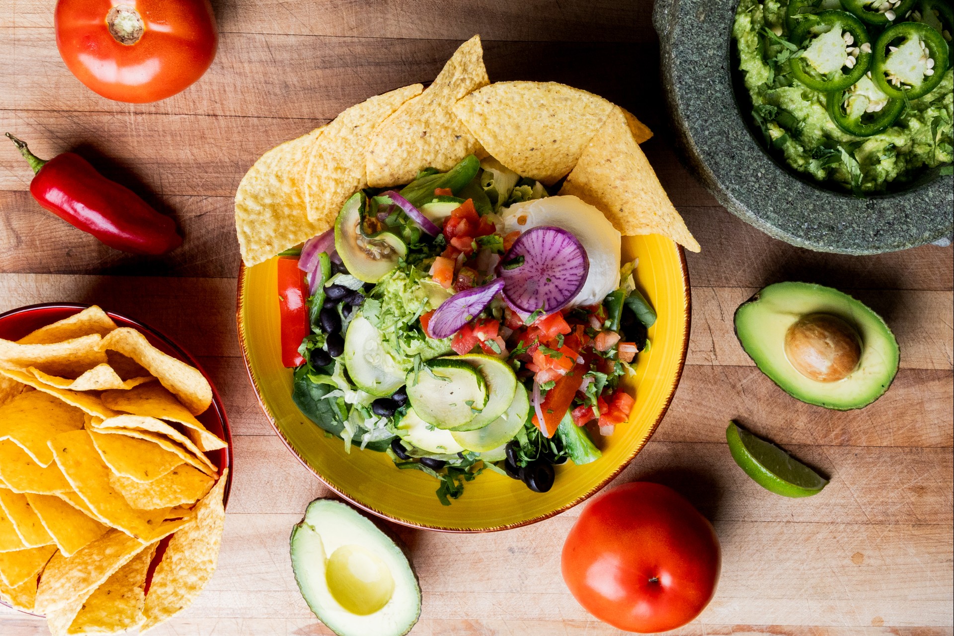 a bowl of salad with chips and avocado