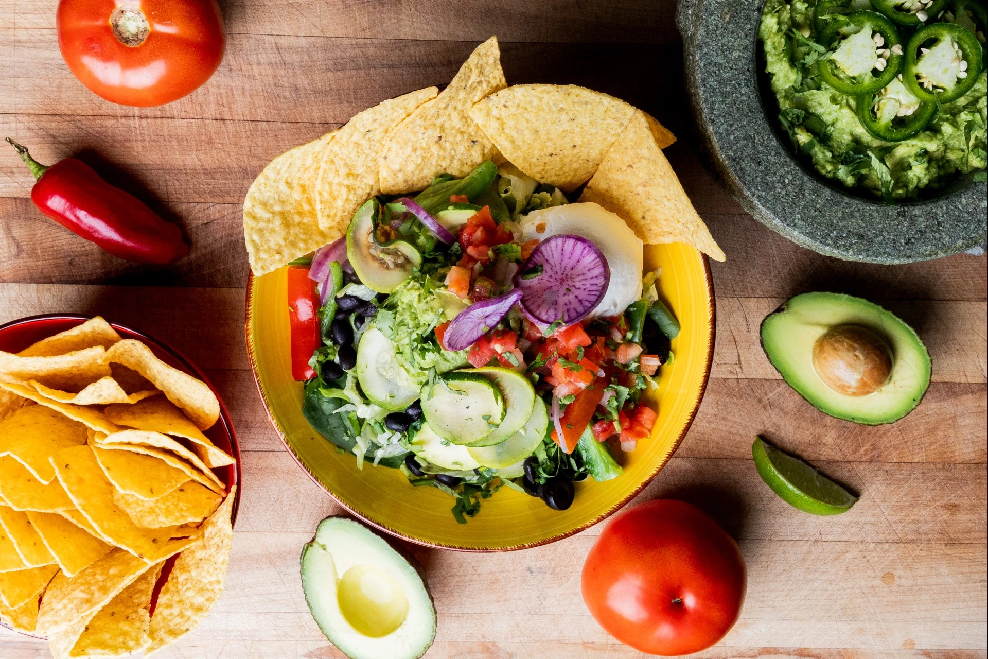 a bowl of salad with chips and avocado