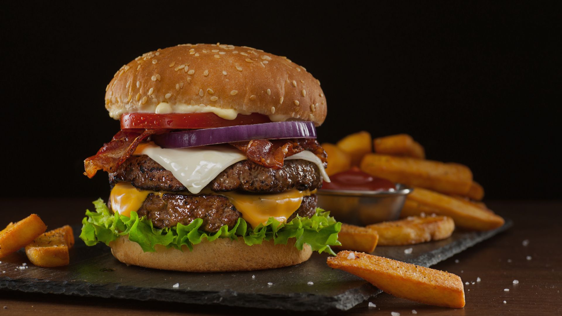 a cheeseburger with fries on a black surface