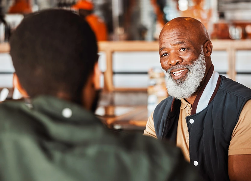 a man with a beard and a white beard talking to another man