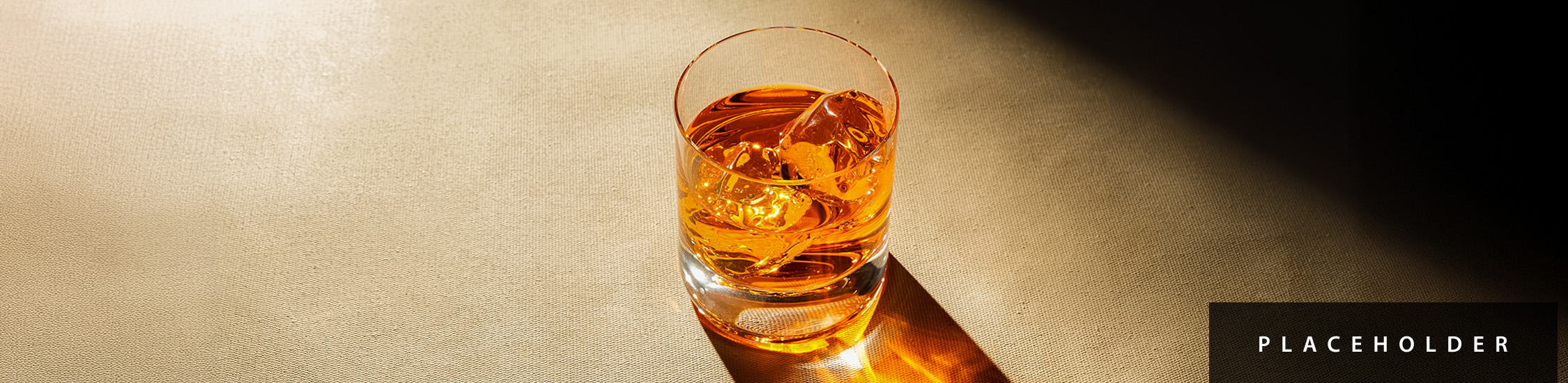 a glass of amber liquid with ice