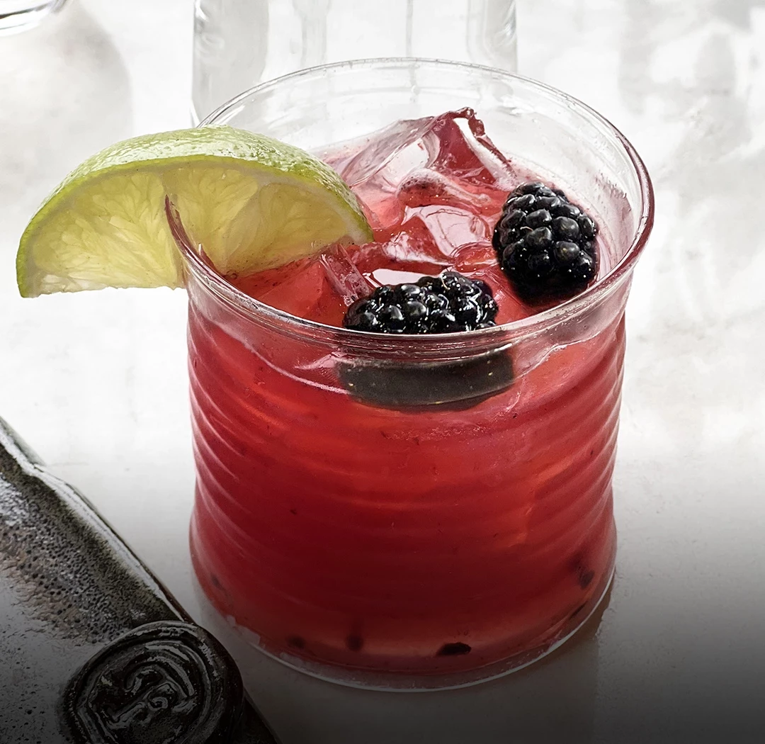 a glass with a drink and fruit on it