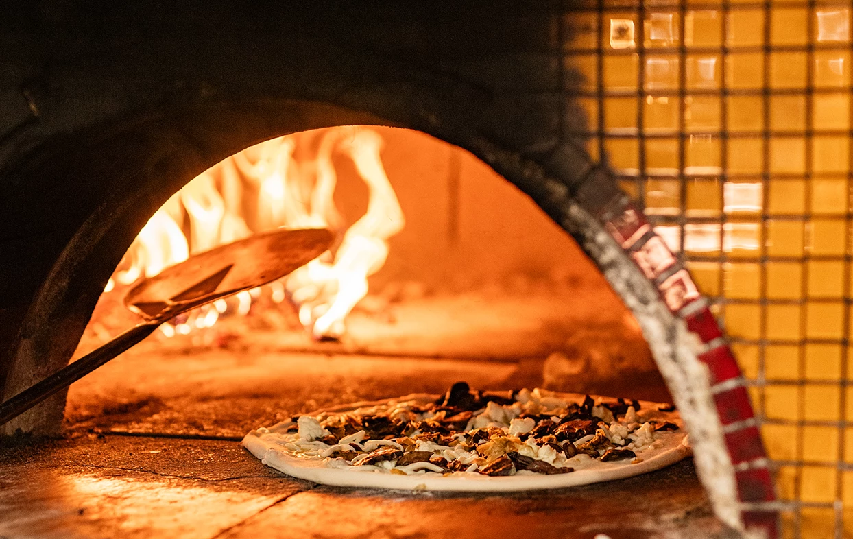 a pizza being cooked in a wood fired oven