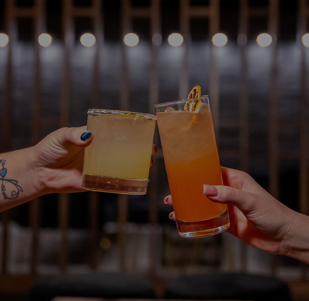 a pair of hands holding glasses of drinks