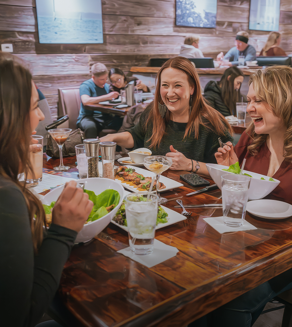 a group of women sitting at a table eating food