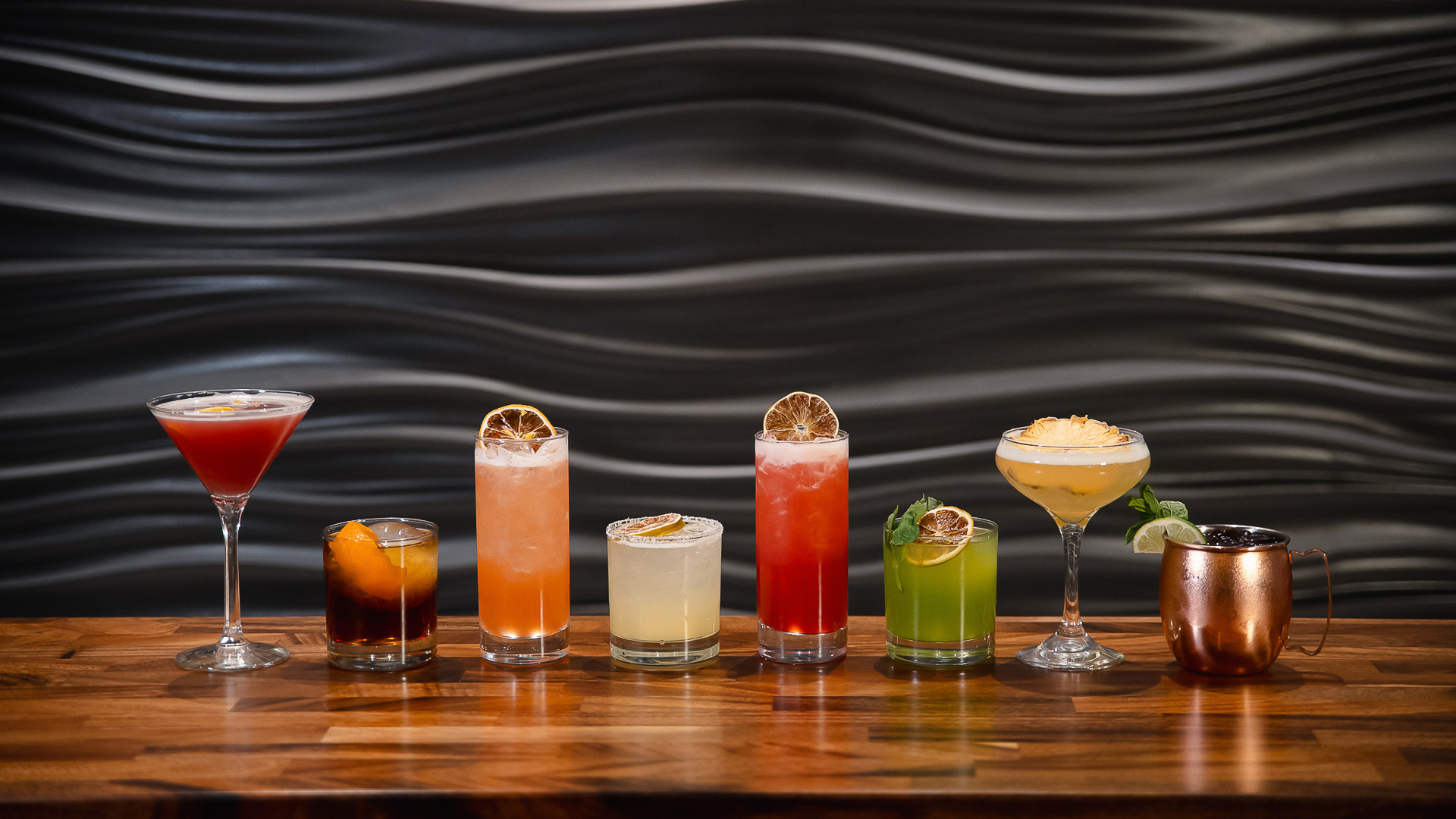 a row of different colored drinks on a table
