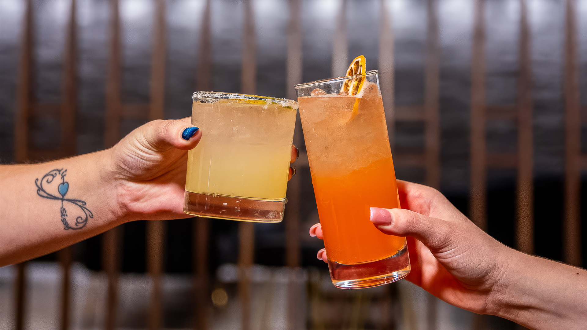 a pair of hands holding glasses of drinks
