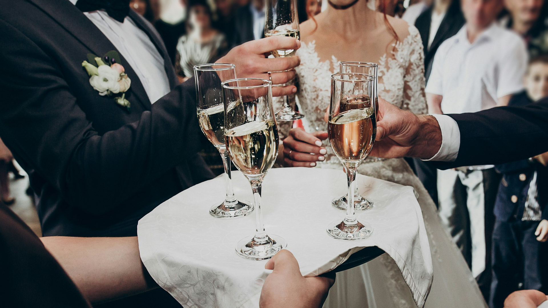 a group of people holding a tray of champagne glasses