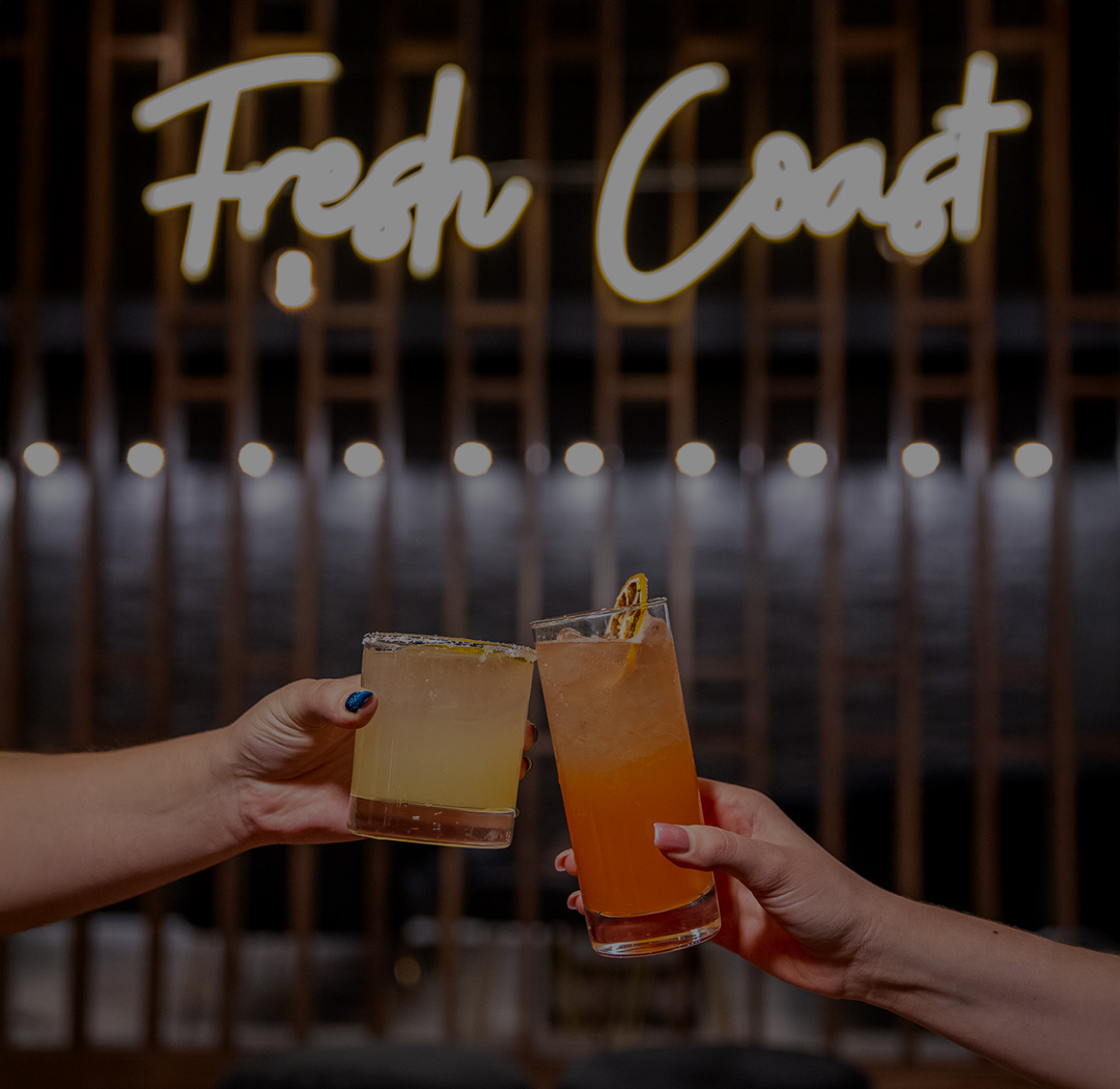 a pair of hands clinking glasses with orange liquid