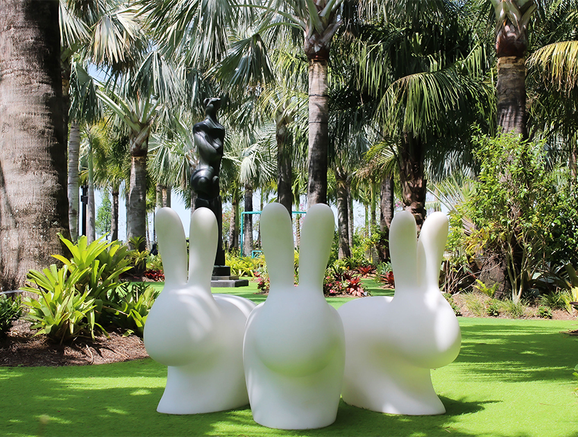 a group of white bunnies in a grassy area with palm trees
