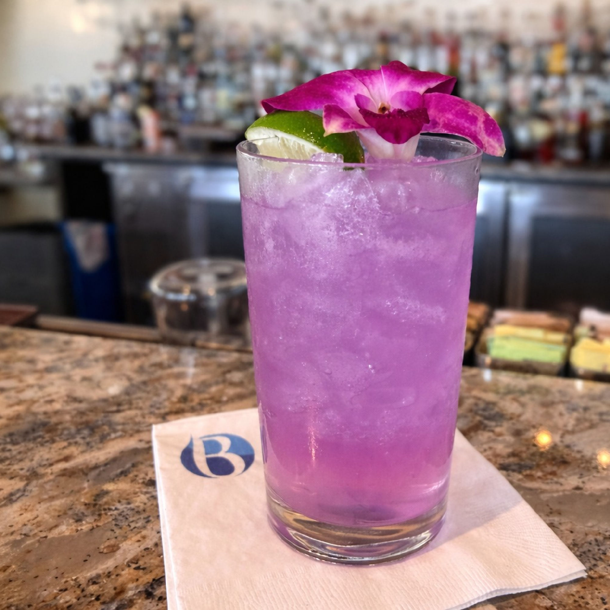 a glass of purple drink with a flower on top