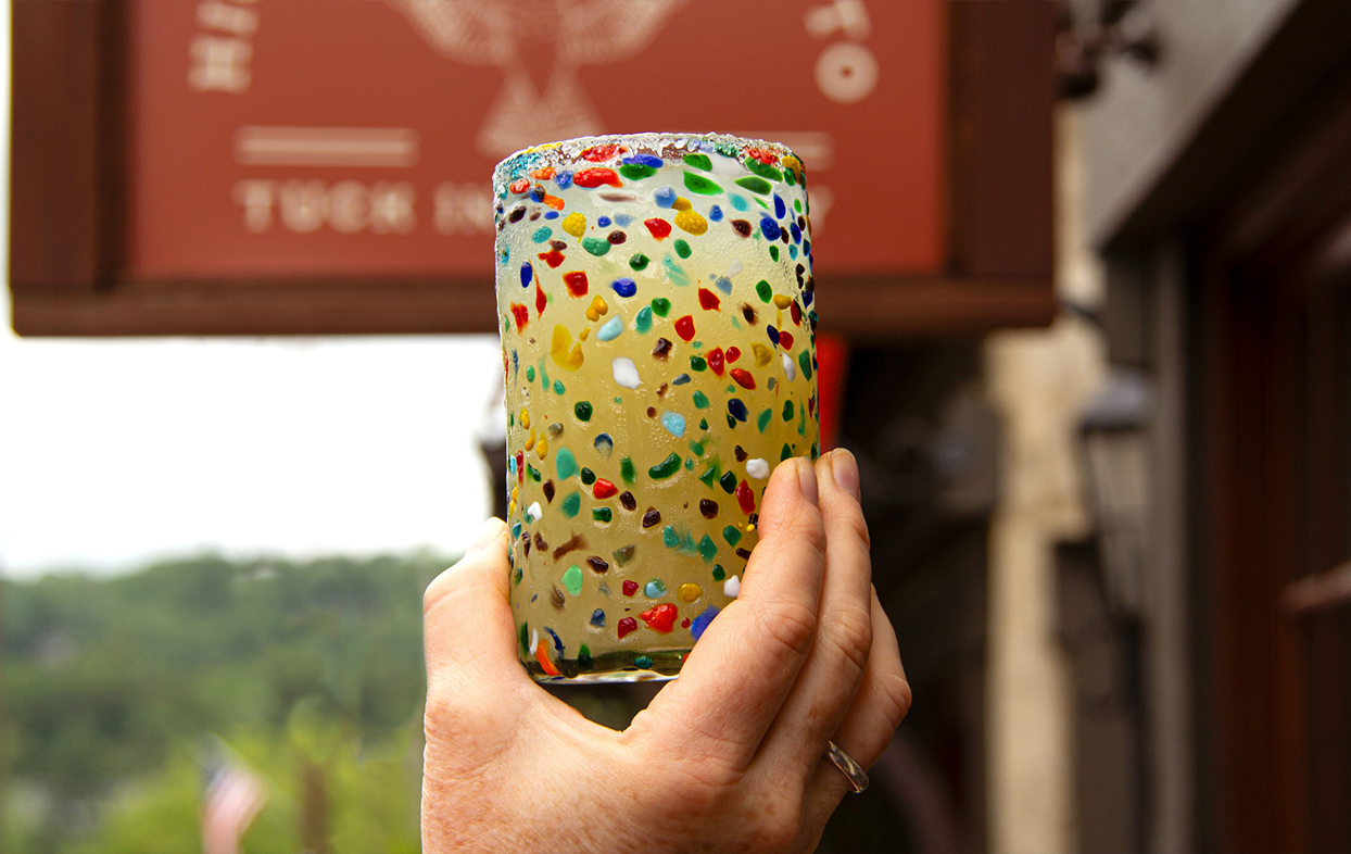 a hand holding a glass with colorful confetti
