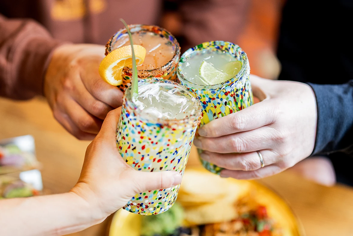 a group of hands holding glasses with drinks