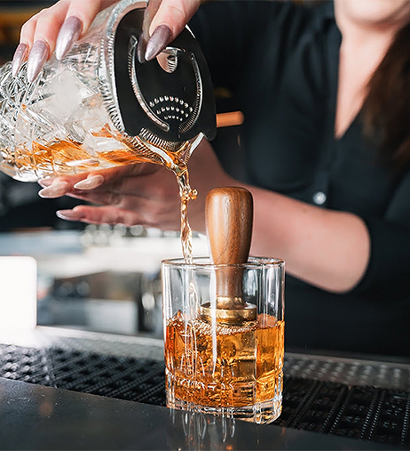a person pouring a drink into a glass