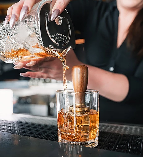 a person pouring a drink into a glass