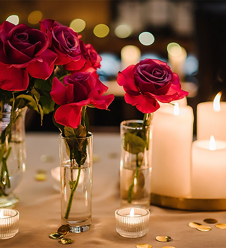 a group of roses in vases with candles