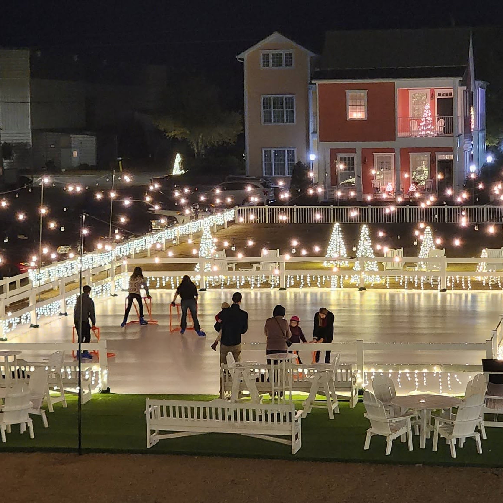 a group of people ice skating on a white deck with lights
