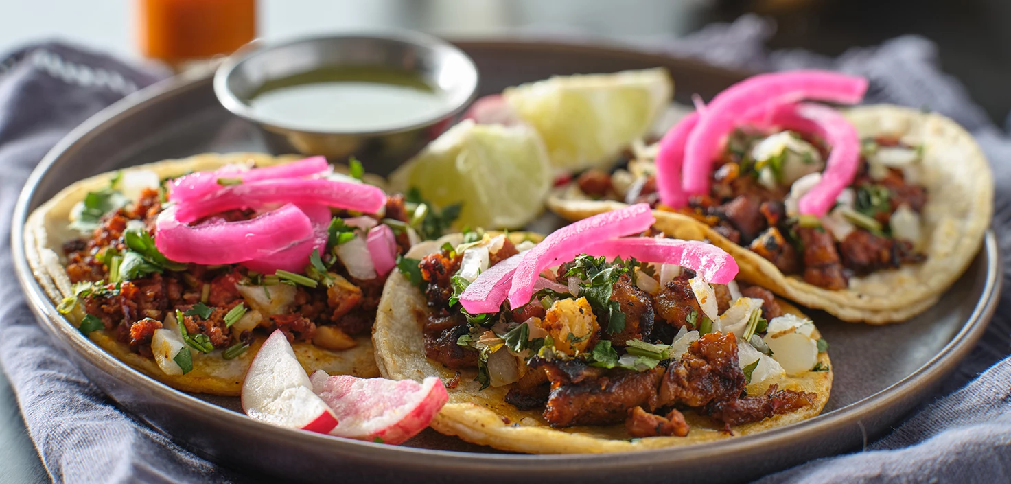 a plate of tacos with onions and lime