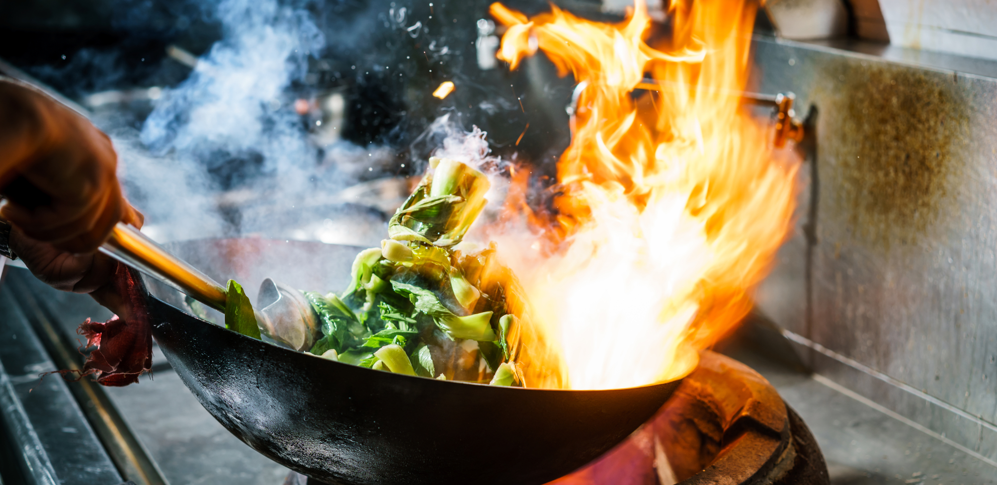 a wok with food on it and flames