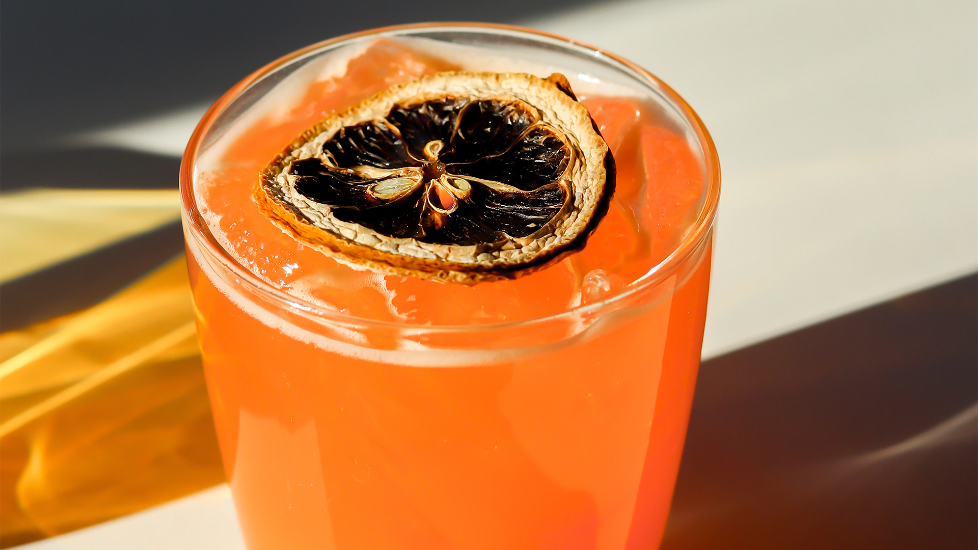 a glass with orange liquid and a slice of dried orange on top