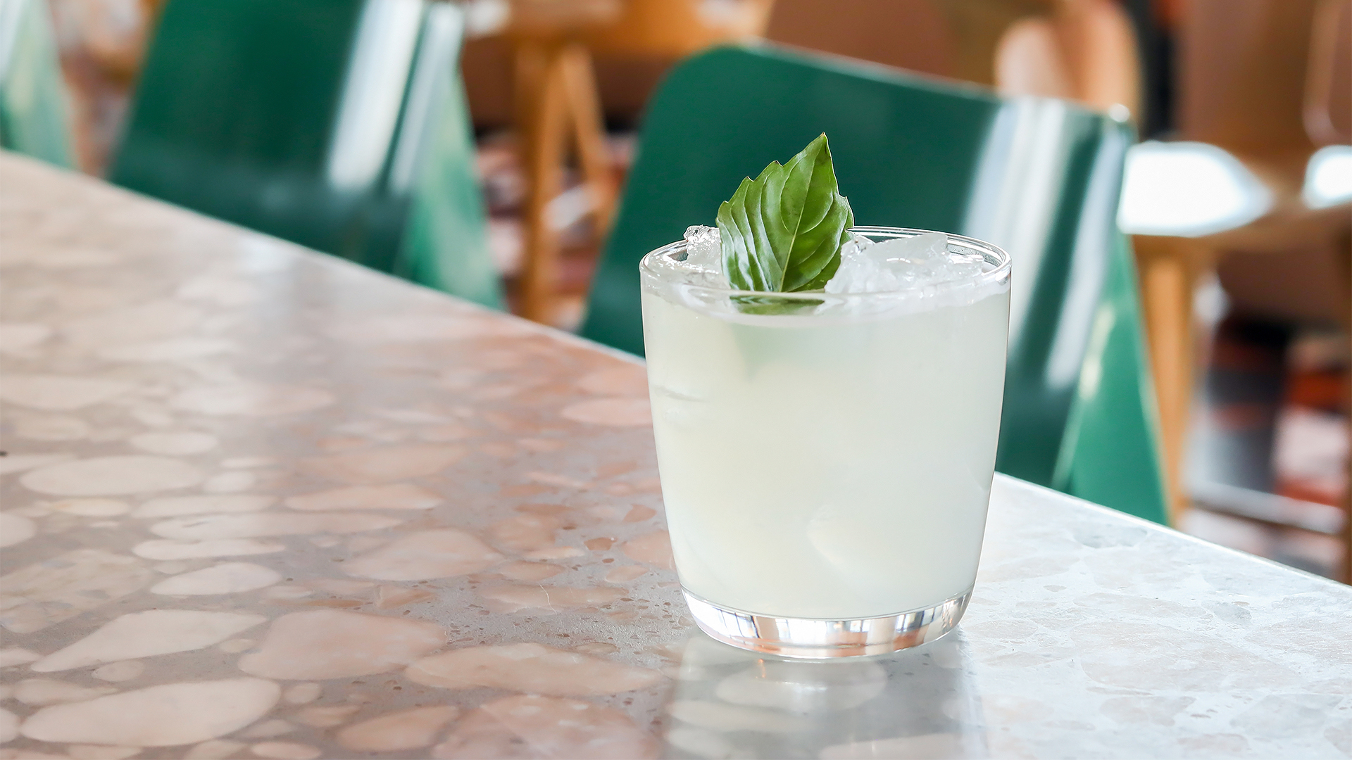 a glass of liquid with ice and a leaf on top